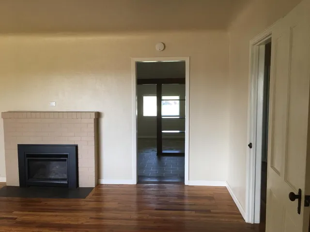 a view of empty room with wooden floor and fireplace