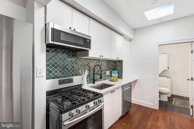 a kitchen with stainless steel appliances a stove and white cabinets
