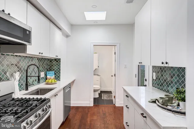 a kitchen with stainless steel appliances granite countertop a stove and a wooden floors