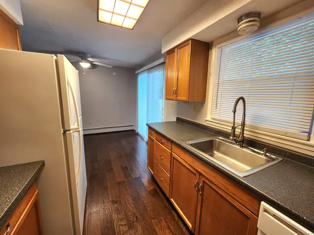 a kitchen with stainless steel appliances granite countertop a sink a refrigerator and wooden floor