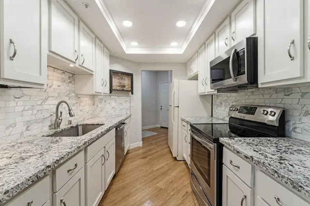 a kitchen with stainless steel appliances granite countertop a sink stove and cabinets