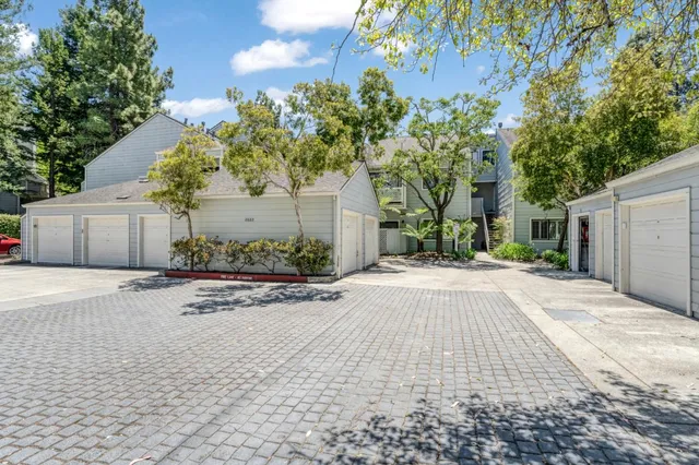 a sidewalk with a building and trees in the background