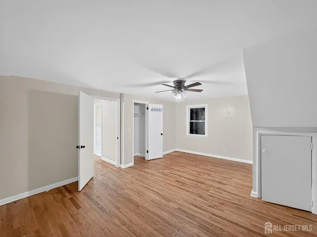 an empty room with wooden floor ceiling fan and window
