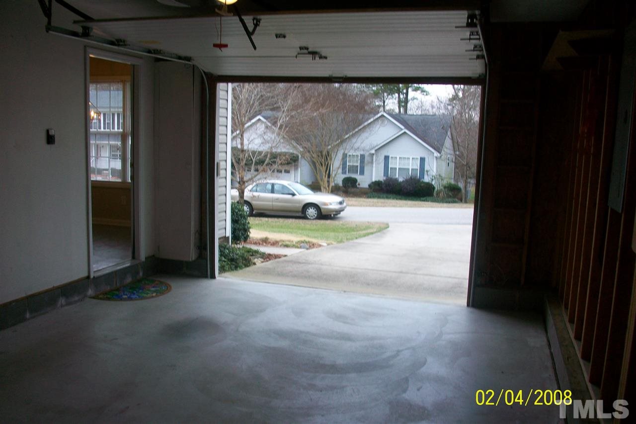 Looking out from over sized, single car garage to drive and parking pad.