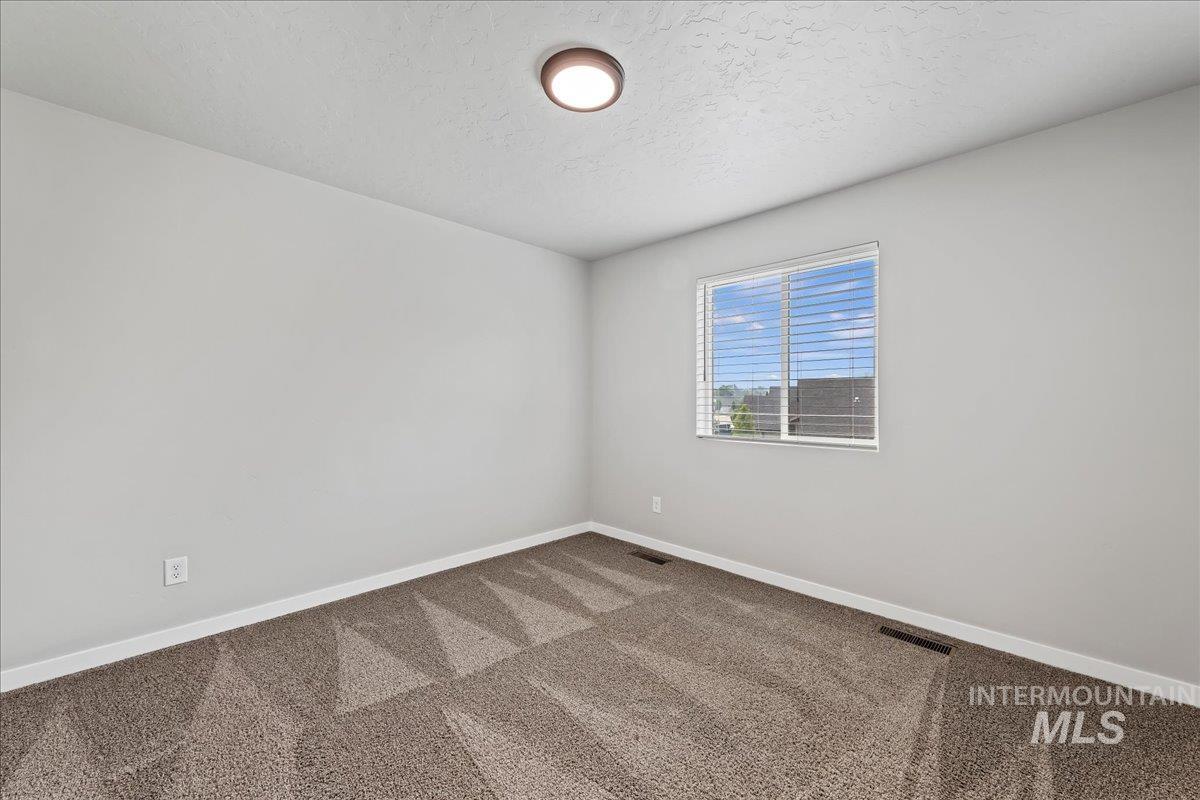 12535 West Victory Road Boise, ID 83709 - Photo 15 of 25 Neutral wall paint, patterned carpeting, and flush-mount ceiling light fixture