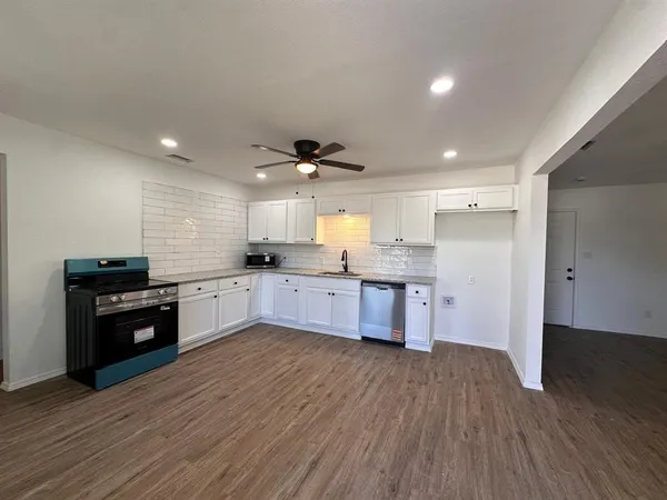 a large kitchen with a wooden floor and stainless steel appliances