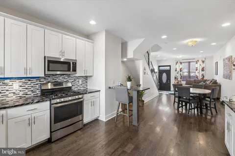 a kitchen with stainless steel appliances a stove a sink a microwave a stove a dining table and chairs