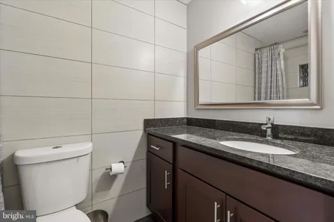 a bathroom with a granite countertop sink a toilet and mirror