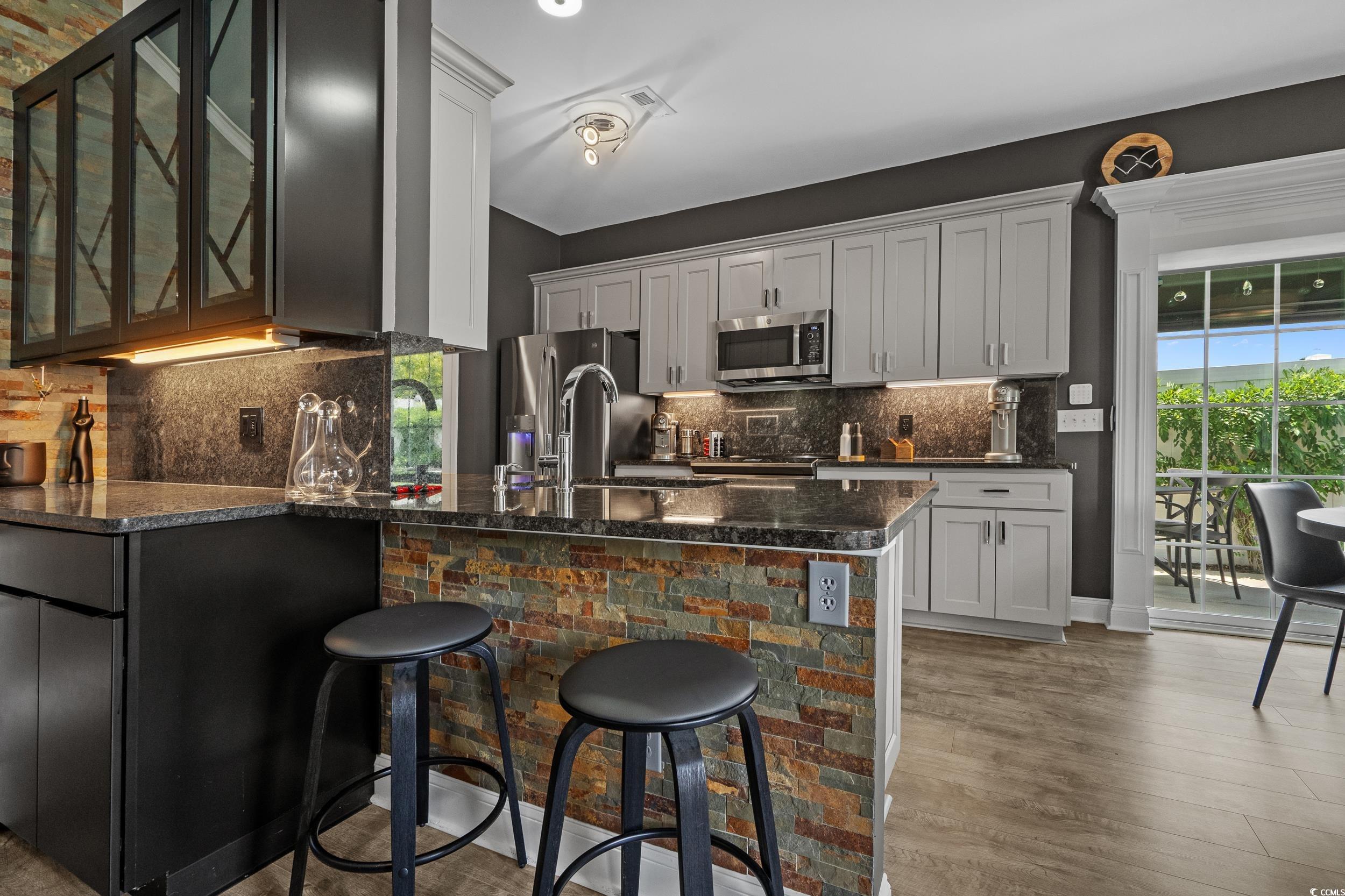 752 Hobonny Loop Longs, SC 29568 - Photo 13 of 40 Kitchen featuring stainless steel appliances, a peninsula, glass insert cabinets, a breakfast bar, and dark stone countertops
