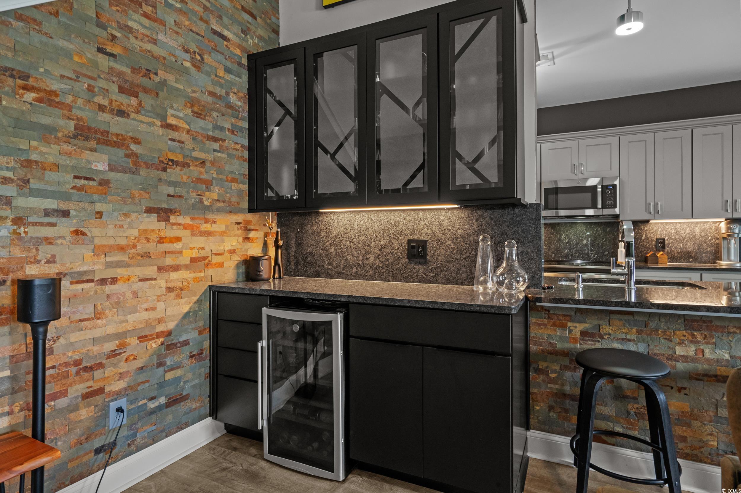 752 Hobonny Loop Longs, SC 29568 - Photo 10 of 40 Indoor bar with beverage cooler, stainless steel microwave, backsplash, and wood finished floors