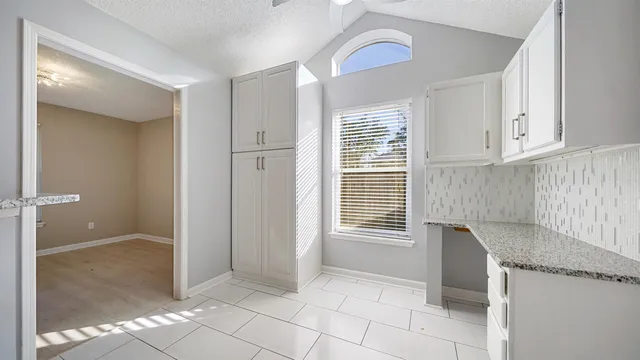 a view of kitchen with granite countertop cabinets and window