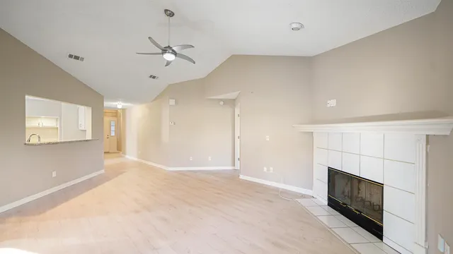 a view of a livingroom with a fireplace a ceiling fan and windows