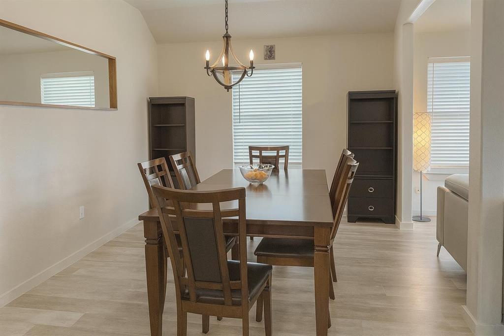 5641 Durst Lane Forney, TX 75126 - Photo 10 of 10 Vaulted ceiling dining area with wood-finish flooring, a contemporary chandelier, multiple windows with blinds, and a built-in wall niche