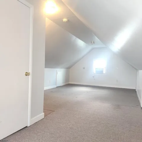 a view of a hallway with wooden floor and a bathroom