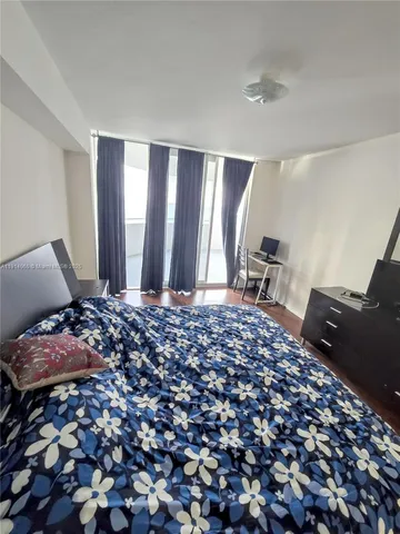 a bed sitting in a bedroom next to a window with pc on the table