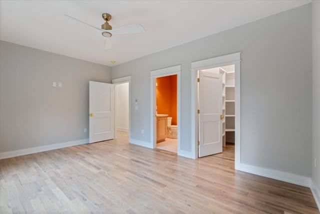 a view of an empty room with wooden floor and closet