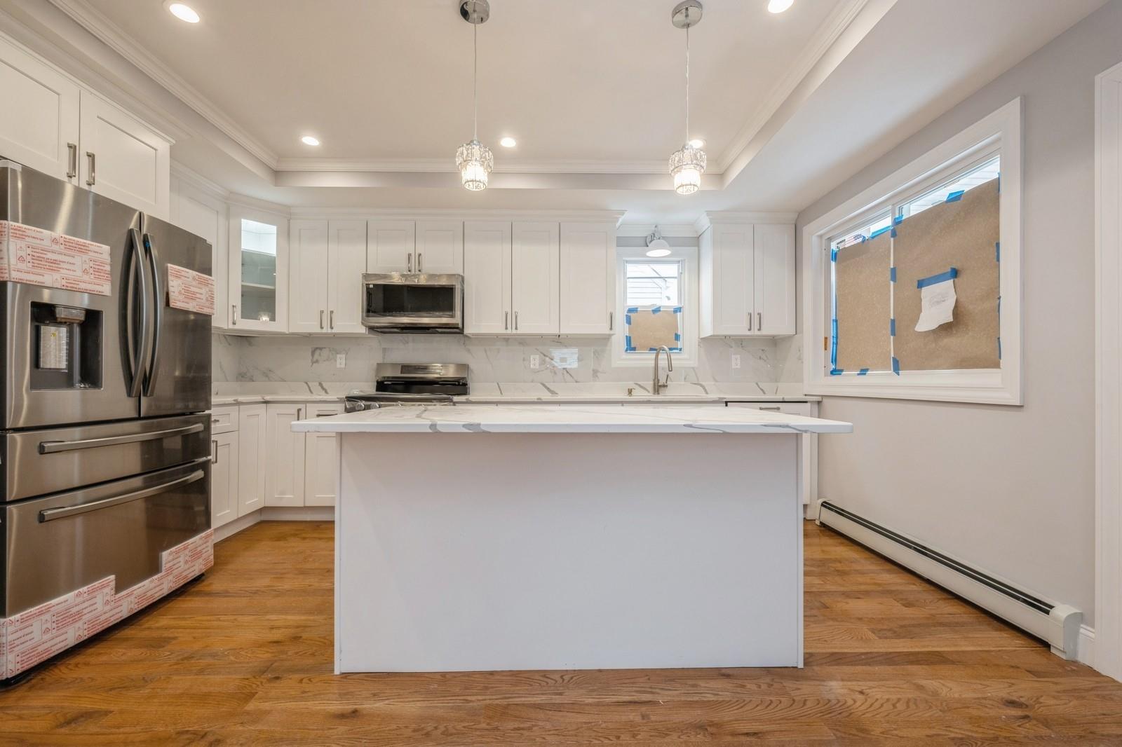 246-59 86th Road Queens, NY 11426 - Photo 14 of 44 Kitchen featuring white cabinetry, appliances with stainless steel finishes, a raised ceiling, and a baseboard heating unit