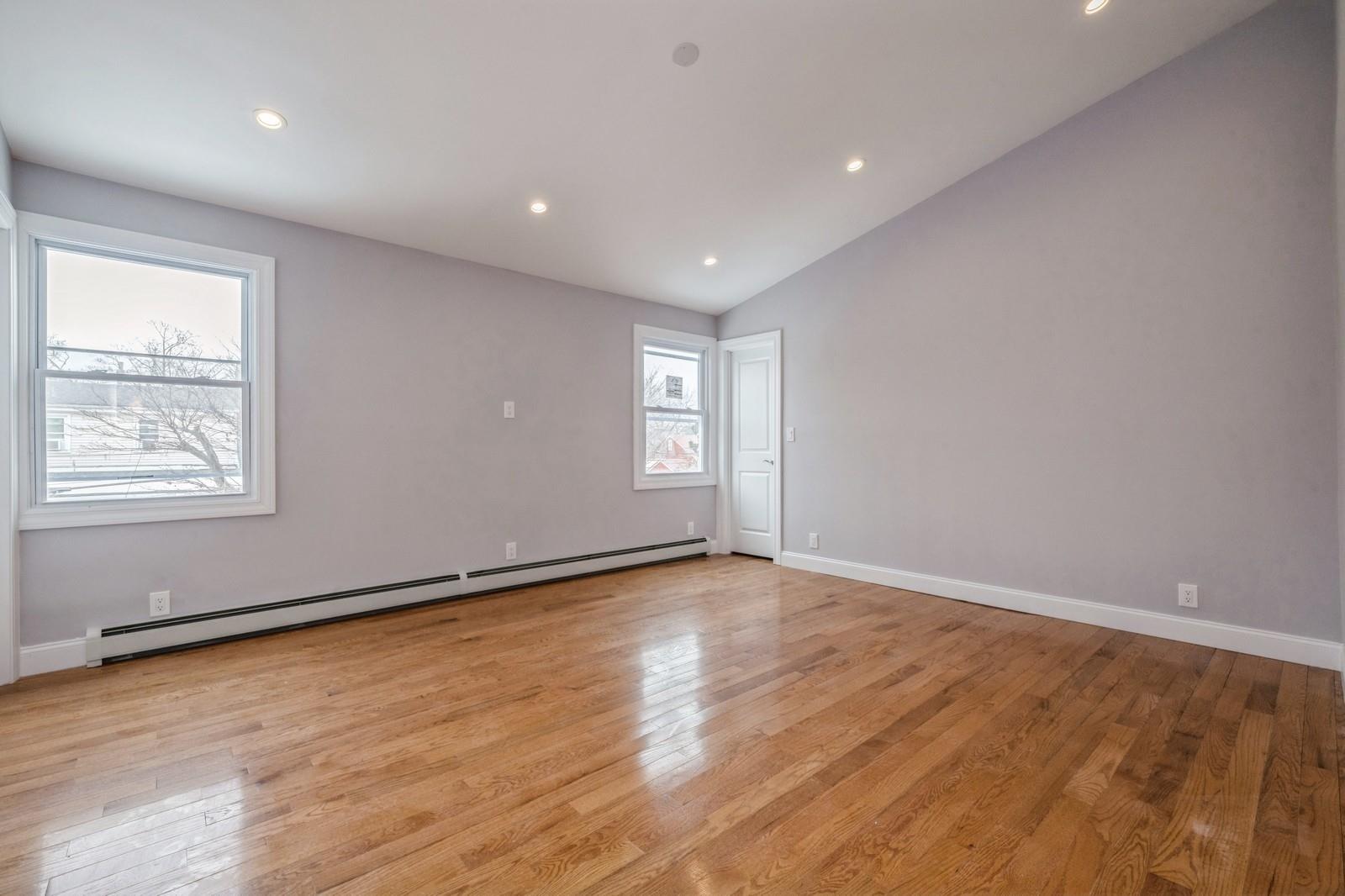 246-59 86th Road Queens, NY 11426 - Photo 29 of 44 Spare room with vaulted ceiling, light hardwood / wood-style floors, and a baseboard heating unit