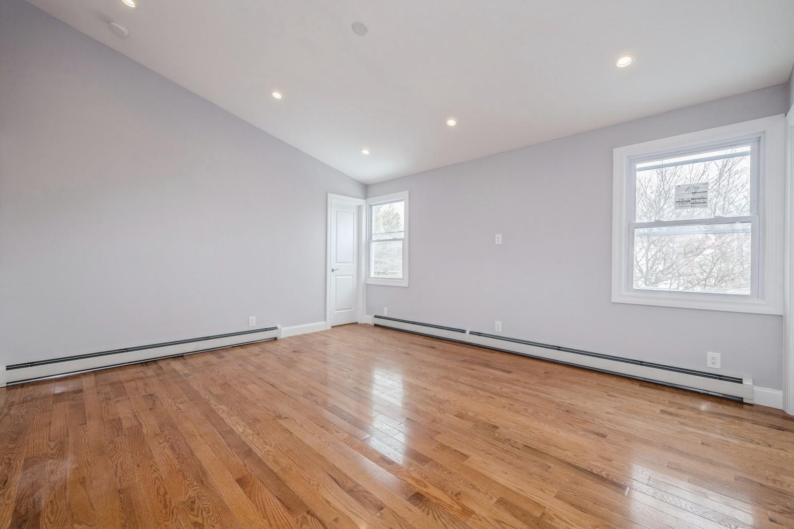 246-59 86th Road Queens, NY 11426 - Photo 30 of 44 Unfurnished room with lofted ceiling, light wood-type flooring, and baseboard heating