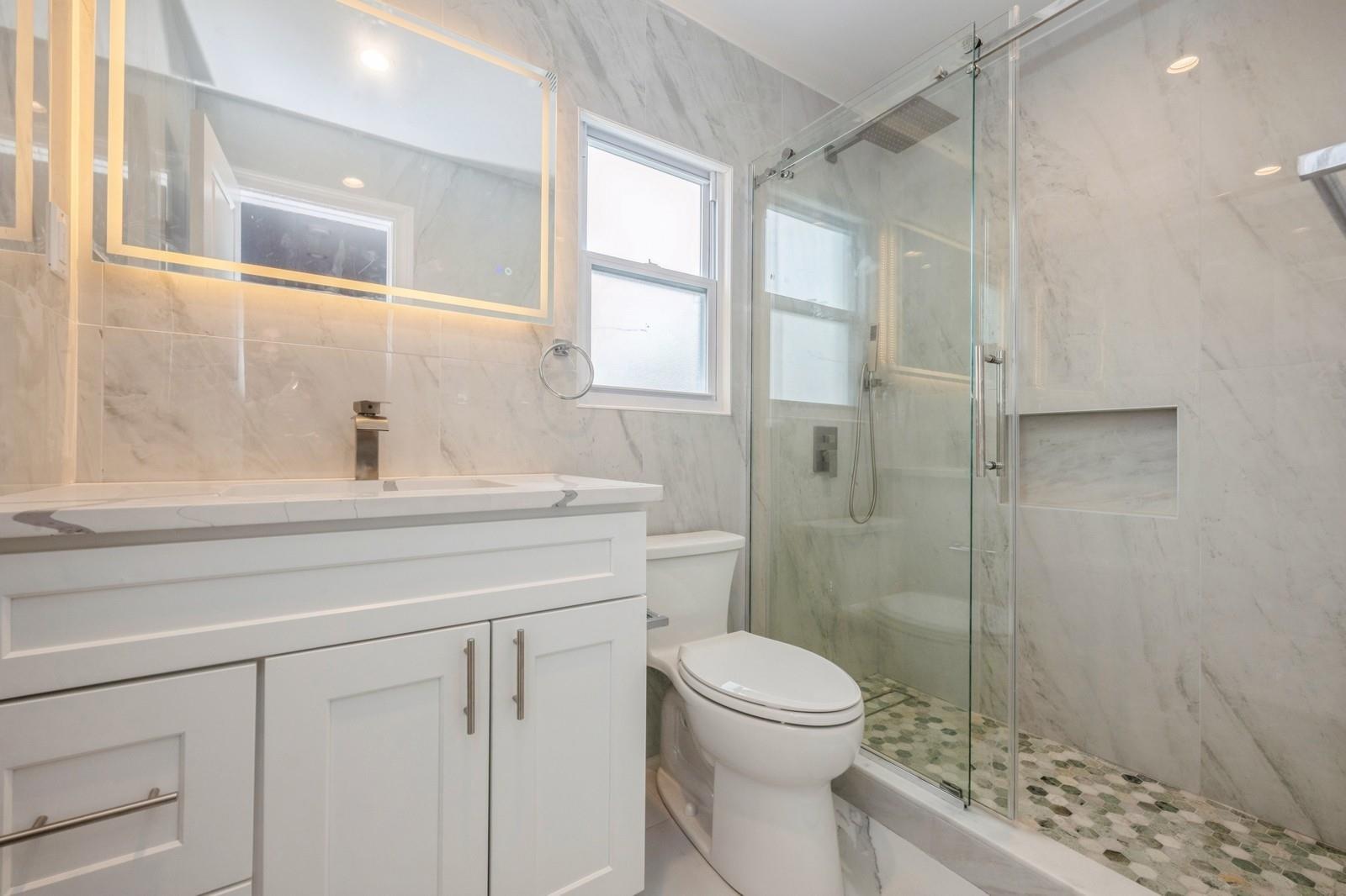 246-59 86th Road Queens, NY 11426 - Photo 33 of 44 Bathroom featuring vanity, tile walls, walk in shower, and toilet