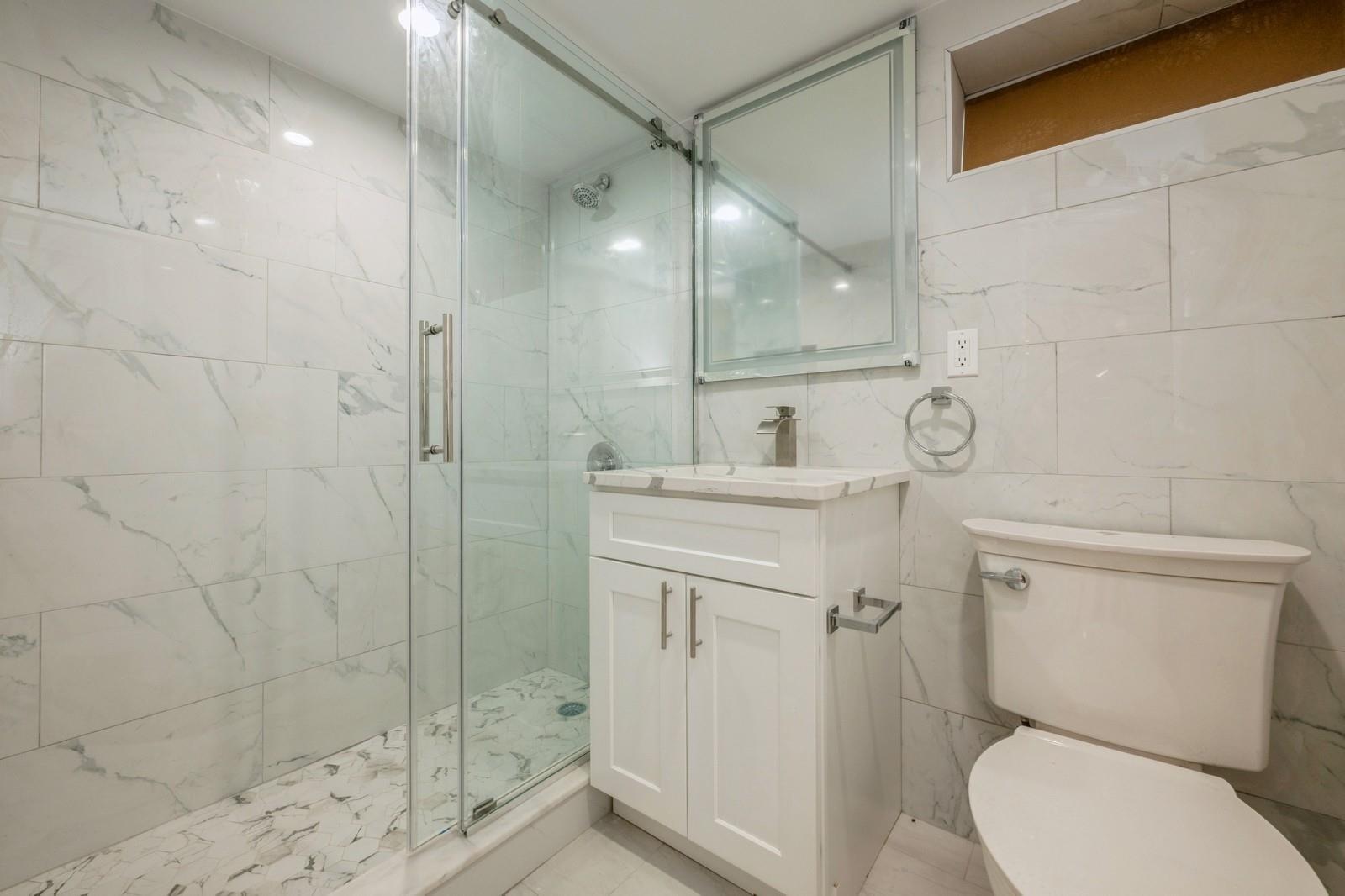 246-59 86th Road Queens, NY 11426 - Photo 39 of 44 Bathroom with tile walls, vanity, toilet, and walk in shower