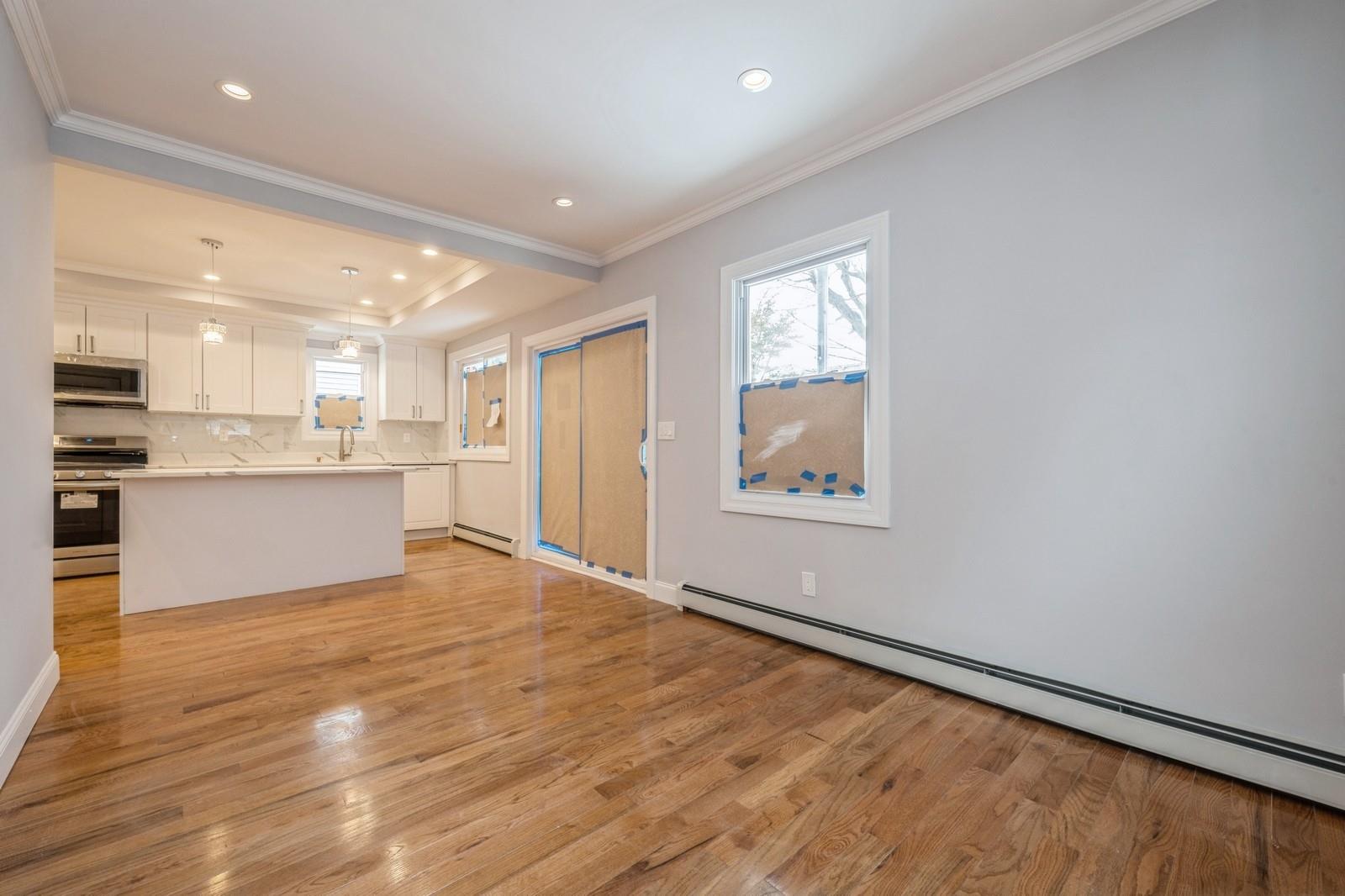 246-59 86th Road Queens, NY 11426 - Photo 9 of 44 Kitchen featuring appliances with stainless steel finishes, a baseboard heating unit, ornamental molding, light hardwood / wood-style floors, and white cabinets