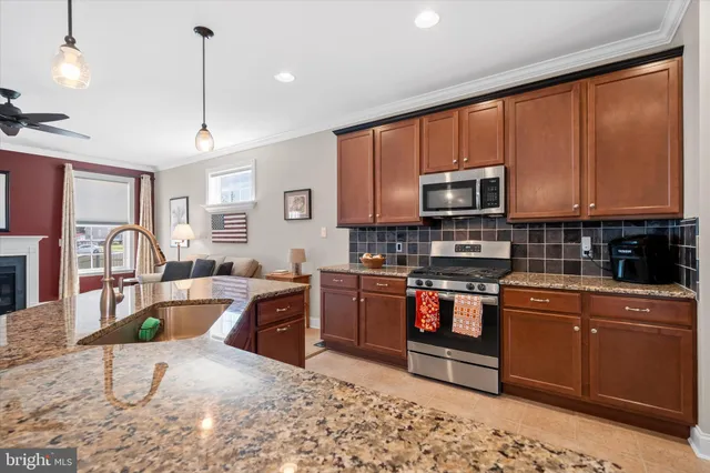 a large kitchen with stainless steel appliances granite countertop a stove top oven a sink dishwasher a dining table and chairs with wooden floor