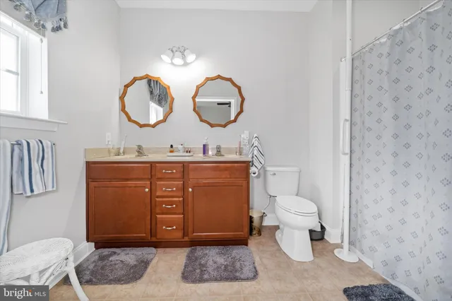 a living room with toilet a sink and a mirror