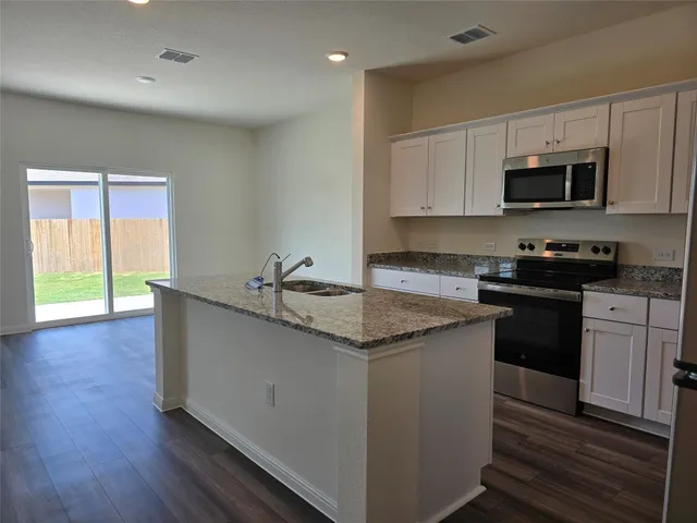 a kitchen with granite countertop a sink and steel appliances