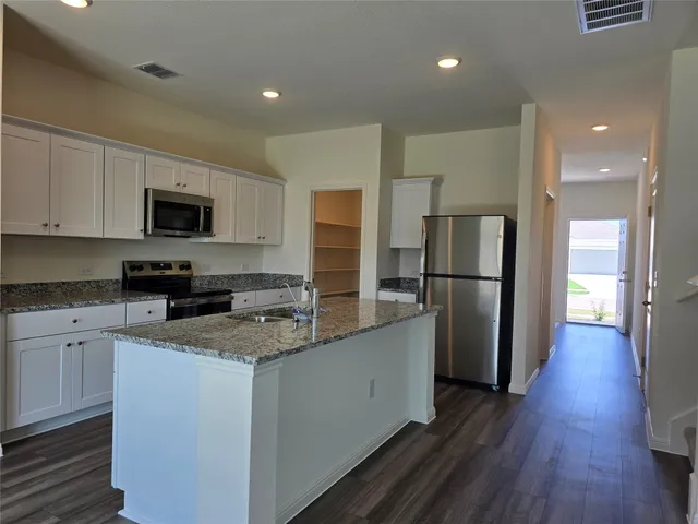 a kitchen with stainless steel appliances granite countertop a refrigerator a stove top oven a sink and dishwasher