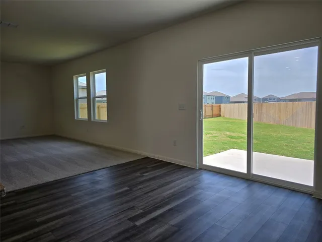 a view of an empty room with wooden floor and a floor to ceiling window