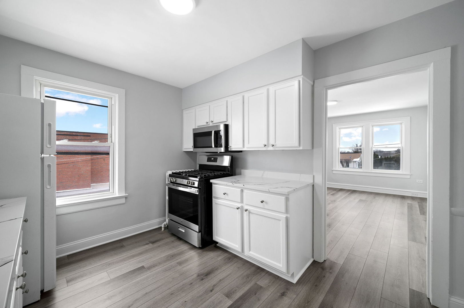 423 Funston Avenue, Unit 2F Highwood, IL 60040 - Photo 5 of 13 a kitchen with stainless steel appliances granite countertop a stove a sink and white cabinets with wooden floor