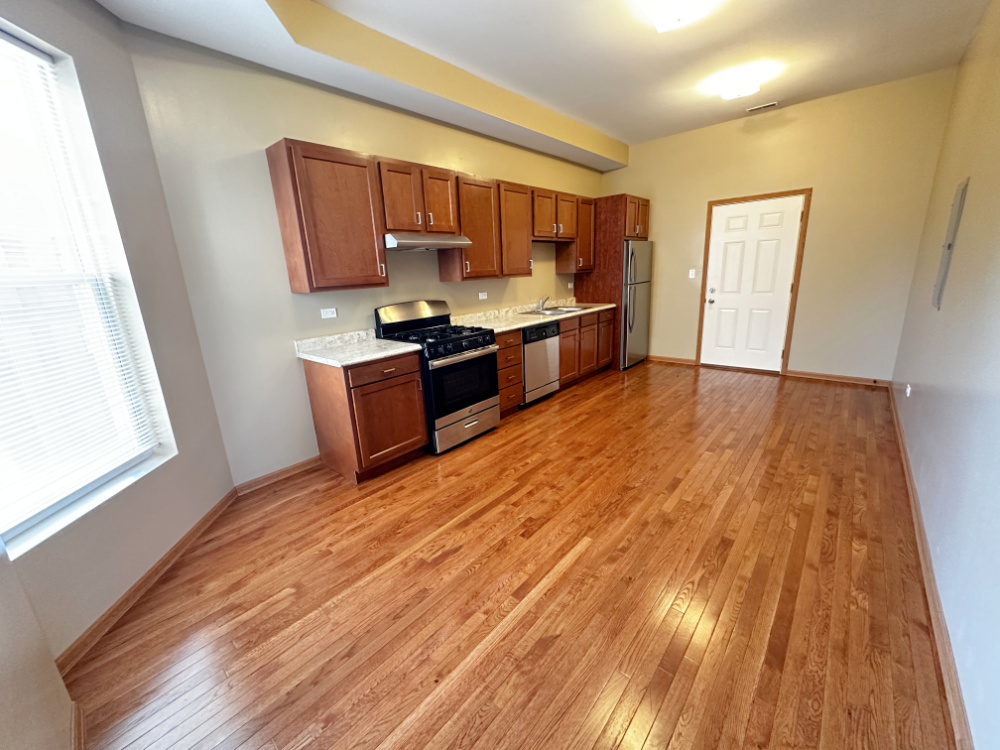 639 West Garfield Boulevard, Unit 3 Chicago, IL 60621 - Photo 3 of 13 a kitchen with stainless steel appliances wooden floors and wooden cabinets