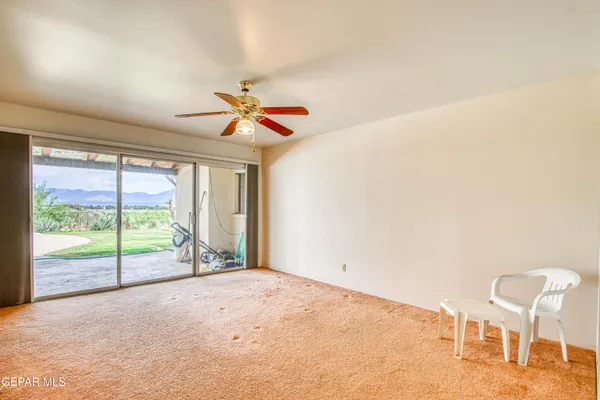 an empty room with chandelier fan and windows