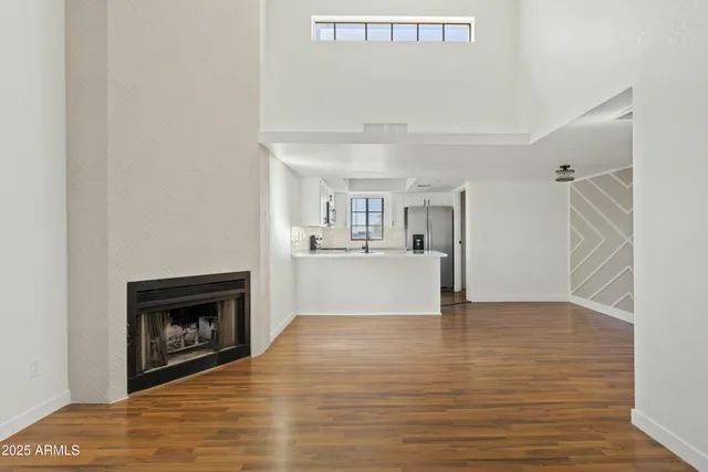 a view of kitchen and empty room with wooden floor