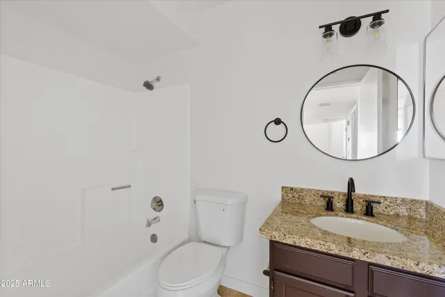 a bathroom with a granite countertop toilet a sink and a mirror
