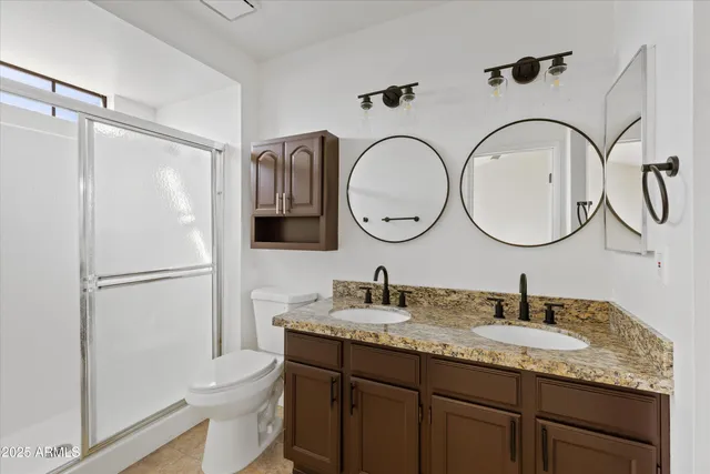 a bathroom with a granite countertop sink a mirror and a toilet