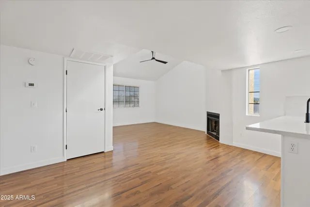 a view of empty room with wooden floor and fan