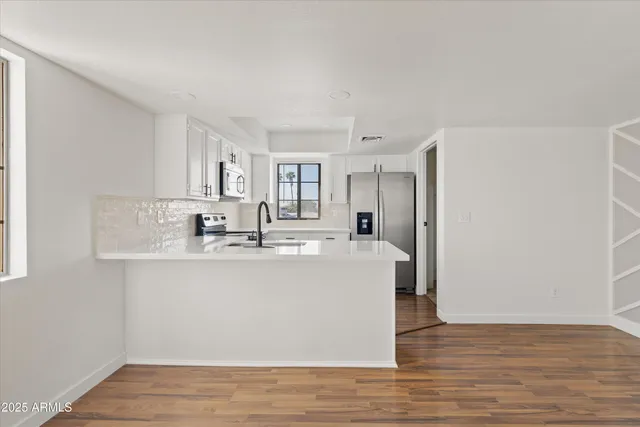 a view of a kitchen with kitchen island a sink wooden floor and a refrigerator