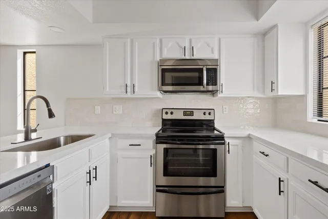 a kitchen with cabinets stainless steel appliances and a sink