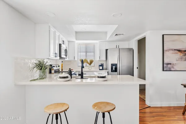 a kitchen with stainless steel appliances a sink a stove a refrigerator cabinets and a dining table