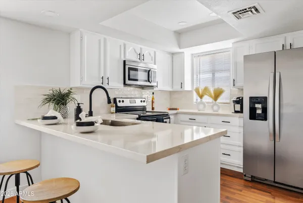 a kitchen with cabinets stainless steel appliances and wooden floor