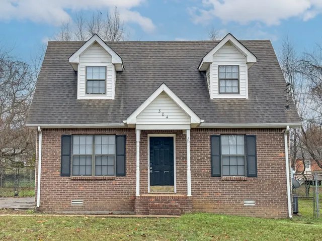 a view of front of a brick house with a yard