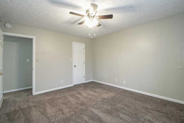 an empty room with a chandelier fan and windows