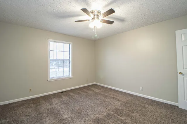 an empty room with windows and fan