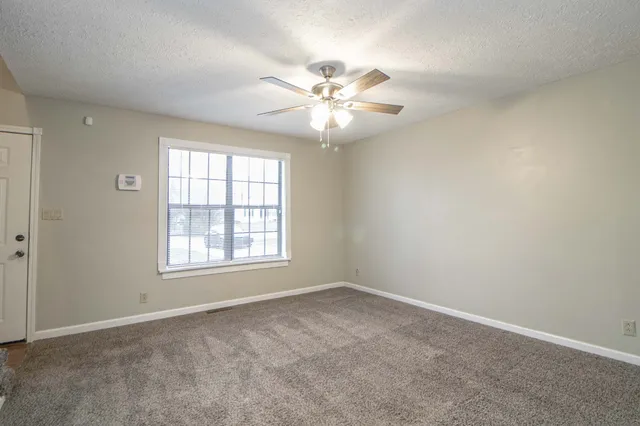 an empty room with windows and fan