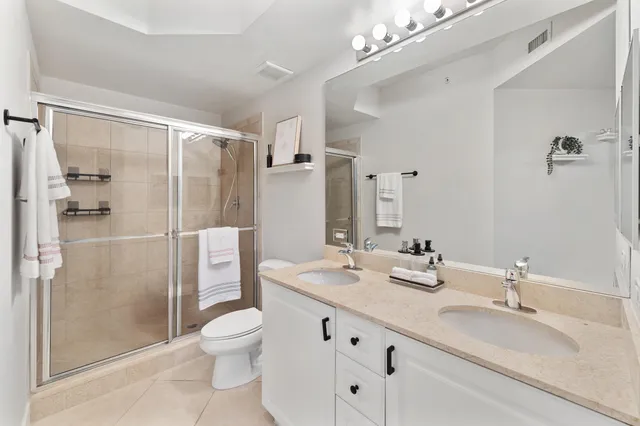 a bathroom with a double vanity sink toilet mirror and shower