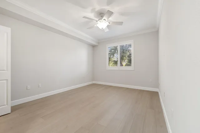 an empty room with windows and ceiling fan