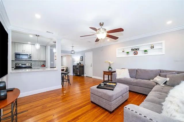 a living room with furniture kitchen view and a wooden floor
