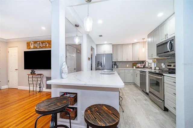 a kitchen with stainless steel appliances granite countertop a sink dishwasher a stove a refrigerator with a dining table and chairs